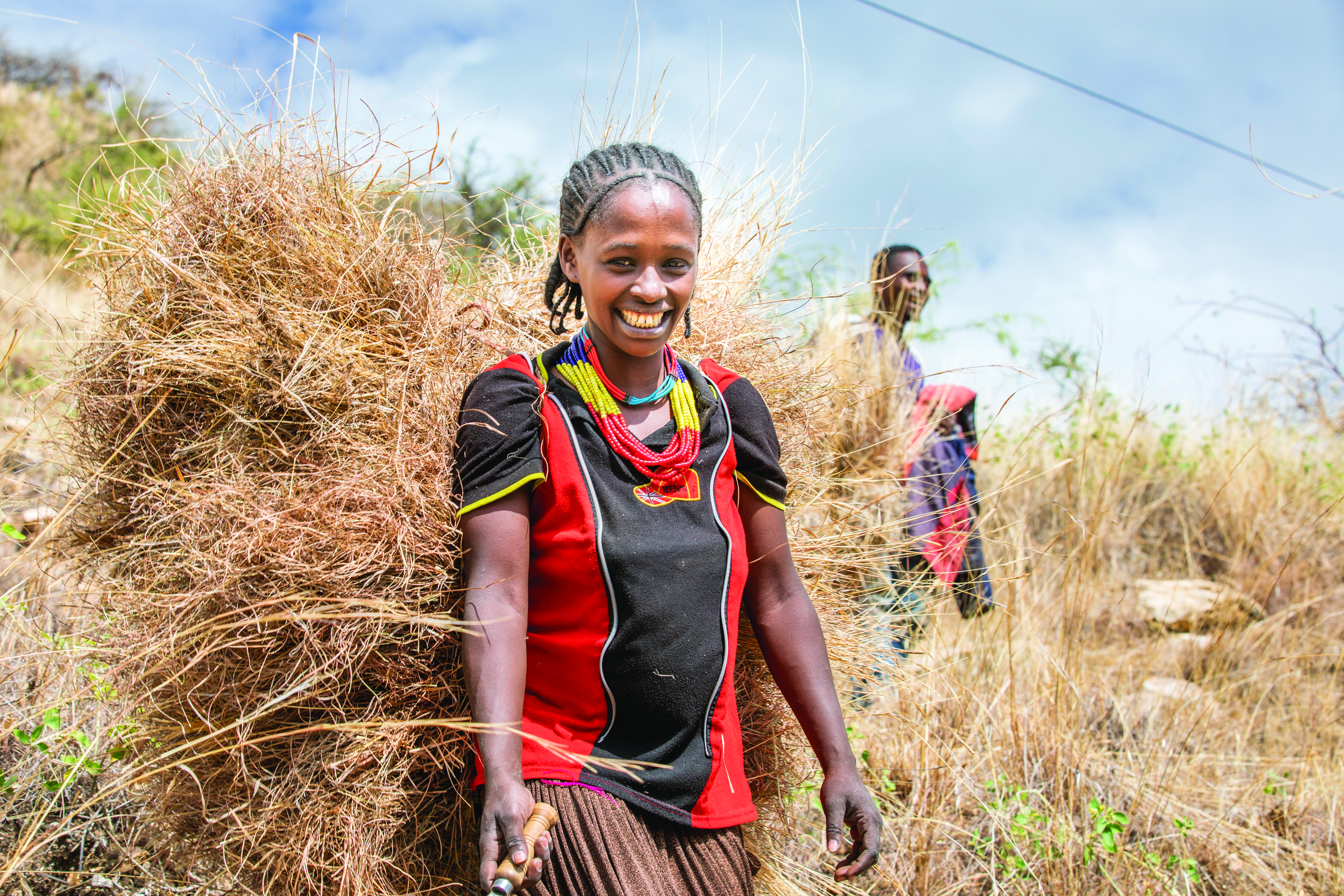 A woman with a bale of grasses on her back.