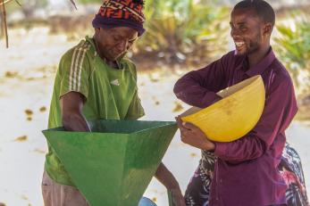 Two people using a grain mill,