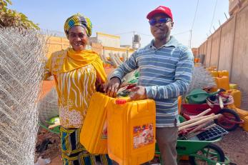Community member and Mercy Corps employee in a marketplace setting.