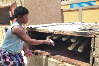 Woman adding bread to oven.