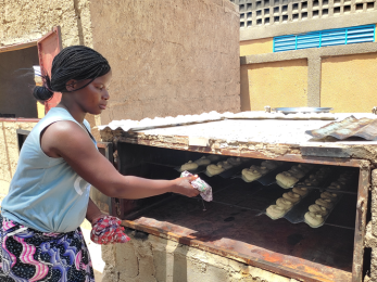 Woman adding bread to oven.